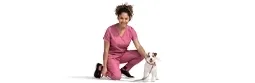 A female vet kneels next to a dog.